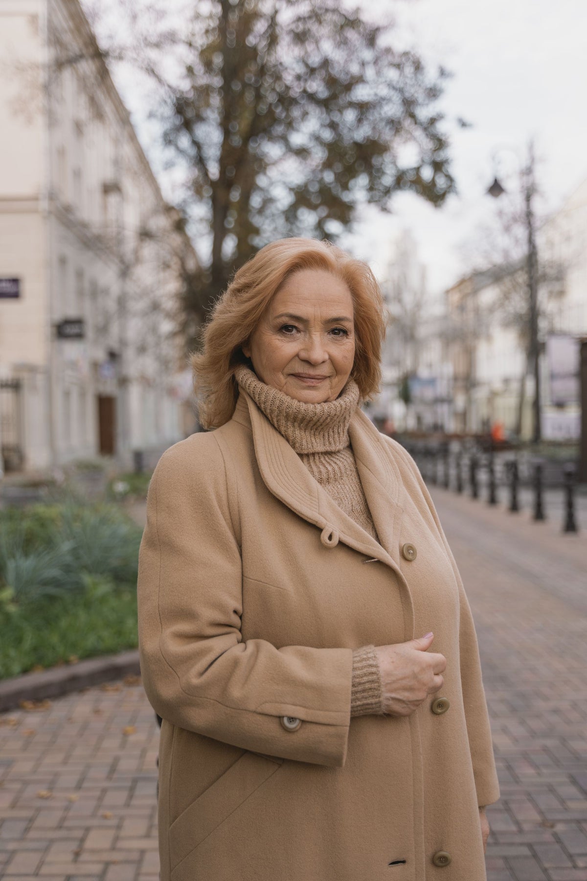 Woman in a camel coat on an autumn city street